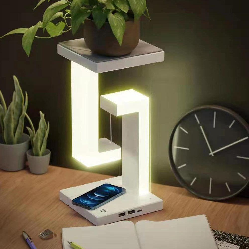 Lampe géométrique blanche éclairant un bureau, avec smartphone sur le socle et plante posée au-dessus