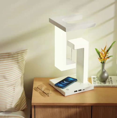 Lampe blanche allumée sur une table de chevet, avec téléphone sur le socle et ports USB visibles
