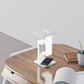 Lampe de bureau blanche au design géométrique, avec smartphone posé sur son socle de charge sans fil